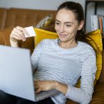 Young woman on couch at home shopping online